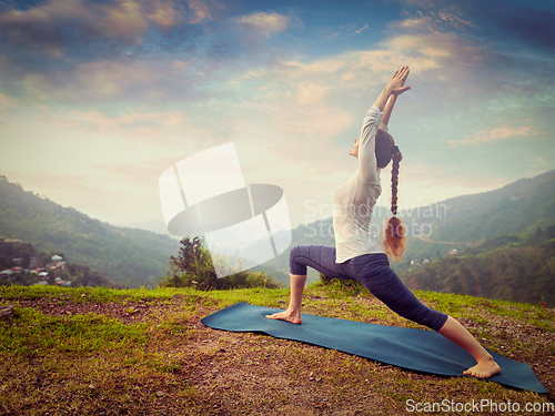 Image of Woman doing yoga asana Virabhadrasana 1 - Warrior pose outdoors