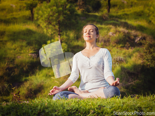 Image of Young sporty fit woman doing yoga Lotus pose oudoors