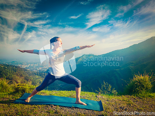 Image of Woman doing yoga asana Virabhadrasana 2 - Warrior pose outdoors