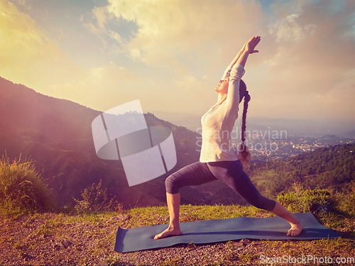 Image of Woman doing yoga asana Virabhadrasana 1 - Warrior pose outdoors