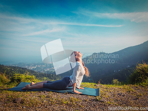 Image of Woman practices yoga asana Urdhva Mukha Svanasana outdoors