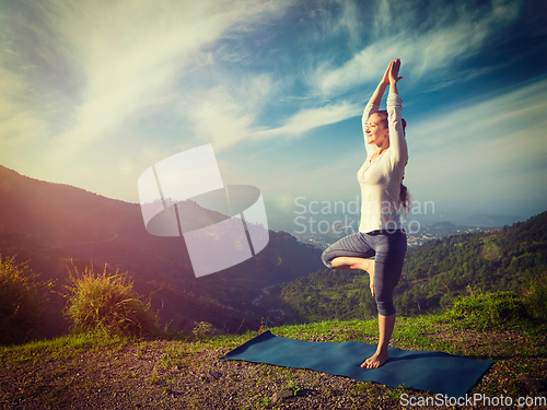 Image of Woman in yoga asana Vrikshasana tree pose in mountains outdoors