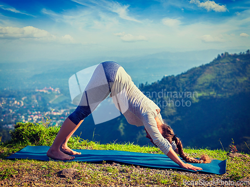Image of Young sporty fit woman doing yoga oudoors in mountains