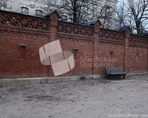 Image of old high brick fence and a bench 