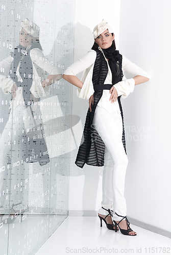 Image of Beautiful young woman in white hat, high heels and white suit is standing, looking in camera. Full length studio shot on white background.