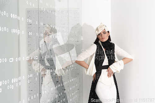 Image of Beautiful young woman in white hat, high heels and white suit is standing, looking in camera. Studio shot on white background.