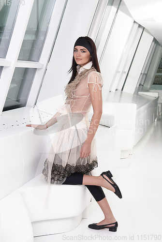 Image of Full-length portrait young elegant woman in black leggings and beige dress. Fashion studio shoot