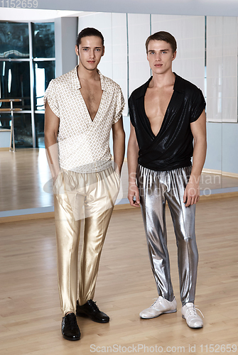 Image of Two men in elegant sport suits posing in fitness gym. Young men in silver and gold sport leggings