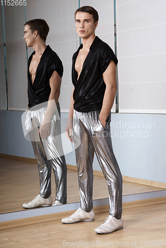 Image of Man in elegant sport suit posing in fitness gym. Young man in silver sport leggings