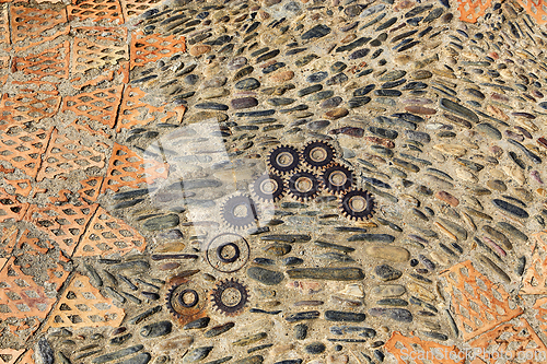 Image of Unusual floor with pattern from pebbles, brick and rusty metal d