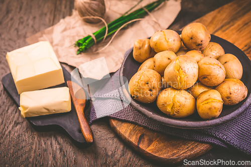 Image of Boiled young potatoes with butter and chives on cutting board