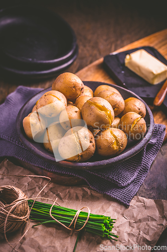 Image of Boiled young potatoes with butter and chives on cutting board