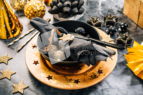 Image of Glamorous black and gold place setting with modern plates for New Years Eve and Christmas