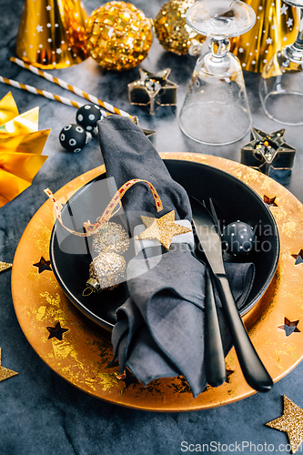 Image of Glamorous black and gold place setting with modern plates for New Years Eve and Christmas