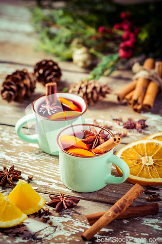 Image of Mulled wine in rustic mugs with spices and citrus fruit