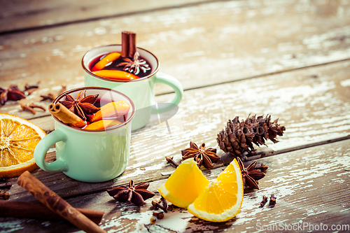 Image of Mulled wine in rustic mugs with spices and citrus fruit