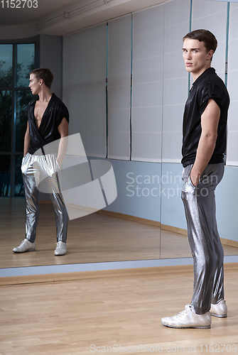 Image of Man in elegant sport suit posing in fitness gym. Young man in silver sport leggings