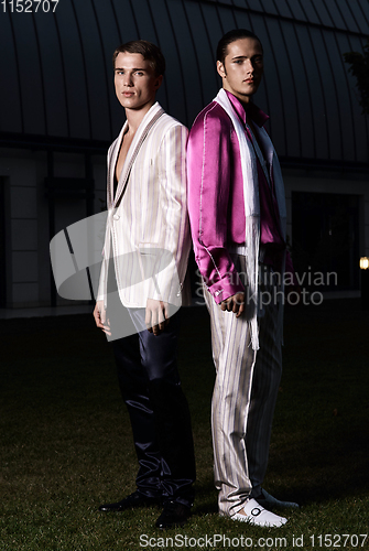 Image of Fashion portrait of two young sexy handsome men models in casual cloth suit on green grass