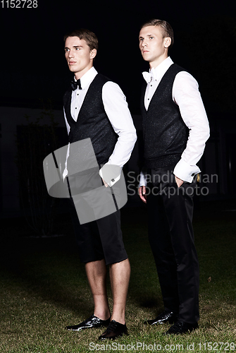 Image of Fashion portrait of two young sexy handsome men models in casual cloth suit on green grass