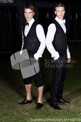 Image of Fashion portrait of two young sexy handsome men models in casual cloth suit on green grass