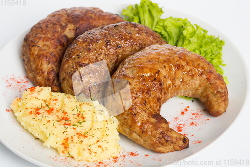 Image of Three fried breaded cutlet with lettuce, mashed potatoes and pepper on white background