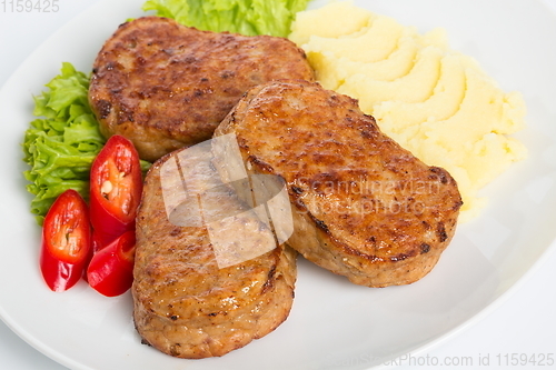 Image of Three fried breaded cutlet with lettuce, mashed potatoes and pepper on white background