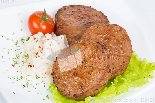 Image of Three fried breaded cutlet with lettuce, tomatoes and rice on white background