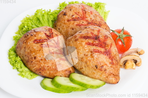 Image of Three fried breaded cutlet with lettuce, tomatoes, cucumbers and mushrooms on white background