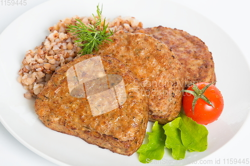 Image of Three fried breaded cutlet with lettuce, tomatoes and buckwheat on white background