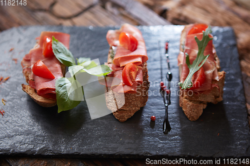 Image of Bruschetta with hamon and sauce on black stone