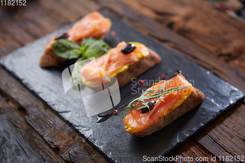 Image of The tasty bruschetta with salmon on black stone