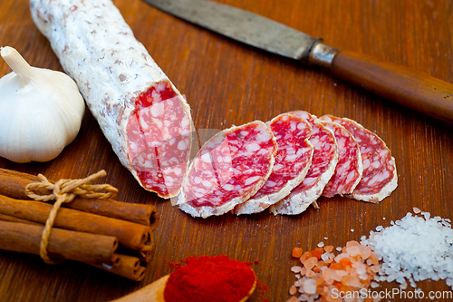 Image of traditional Italian salame cured sausage sliced on a wood board