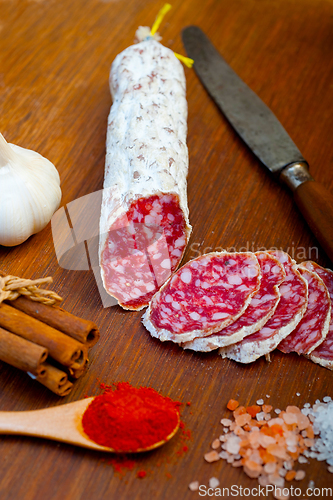 Image of traditional Italian salame cured sausage sliced on a wood board