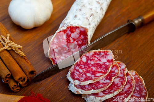 Image of traditional Italian salame cured sausage sliced on a wood board