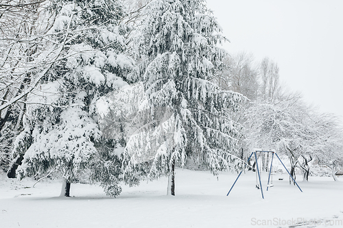 Image of Child swing set dusted with snow in a snow covered parkland