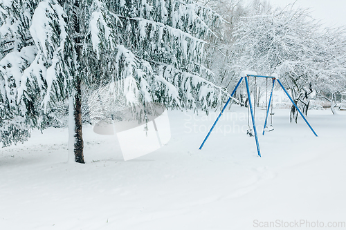 Image of Swing set and trees in a park dusted and covered with fresh whit