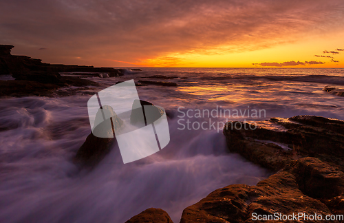 Image of Ocean waves surging over rocky coast with incoming tide