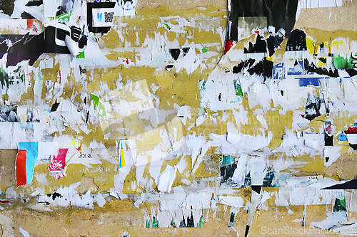 Image of Dirty street yellow wall with old torn and peeling poster paper 