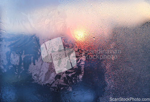 Image of Ice pattern, water drops and sunlight on a frozen winter window