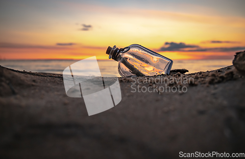 Image of Message in the bottle against the Sun setting down