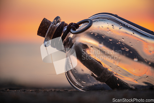 Image of Message in the bottle against the Sun setting down