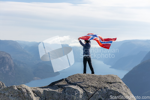 Image of Woman with a waving flag of Norway on the background of nature