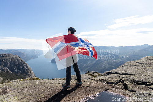Image of Woman with a waving flag of Norway on the background of nature