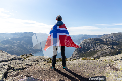 Image of Woman with a waving flag of Norway on the background of nature