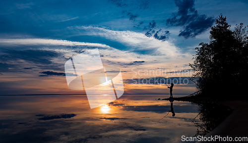 Image of Woman fishing on Fishing rod spinning at sunset background.