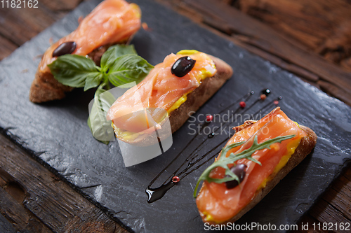 Image of The tasty bruschetta with salmon on black stone