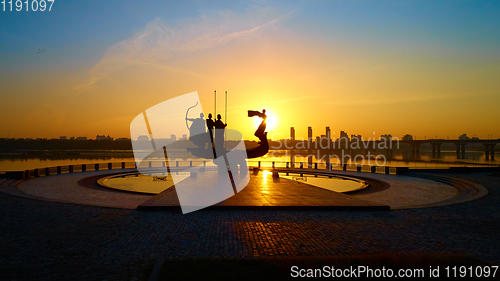 Image of Monument to the founders of Kyiv at sunrise, wide-angle view with blue sky and yellow sun. Statue of Kyi, Shchek, Horyv and Lybid.