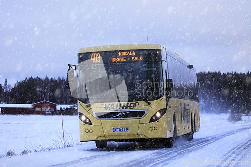 Image of Yellow Volvo Bus Transports Passengers in Winter Snowfall