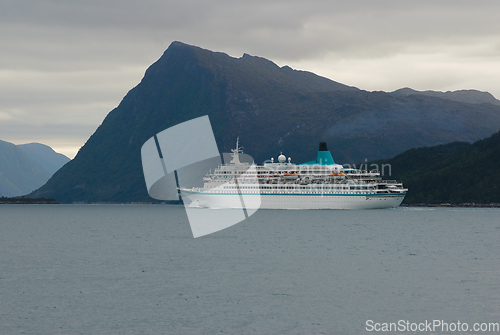 Image of tourist ship sails into a fjord with mountains