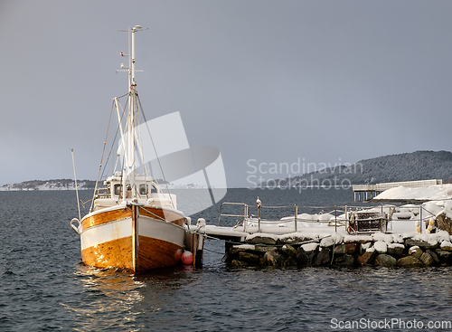 Image of fishing boat at stone quay in winter